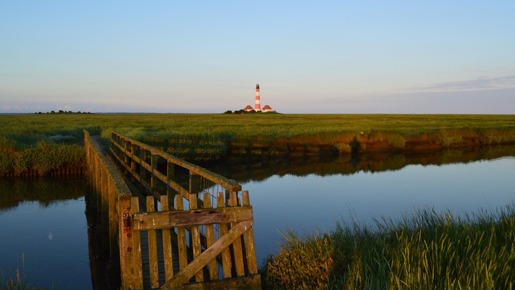 Das Bild zeigt eine Brücke über einen Priel nahe dem Westerhever Leuchtturm